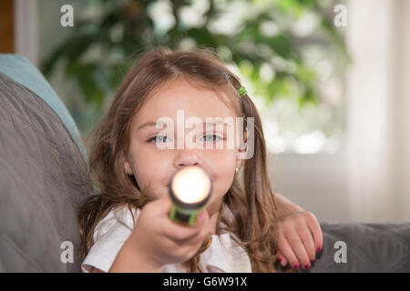 Kleinkind spielt mit einer Taschenlampe. Stockfoto