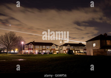 FOTO MIT LANGSAMER VERSCHLUSSZEIT Lichtspuren eines Flugzeugs, das über Häuser im Dorf Bedfont im Großraum London fliegt, während es am Flughafen Heathrow landet. Stockfoto