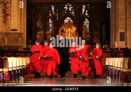 Chöre des Ely Cathedral Chores und des Reverend Mark Bonney nehmen an traditionellen Pfannkuchen-Rennen vor dem abendlichen Gesang in der Kathedrale in Cambridgeshire Teil. Stockfoto