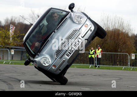 Ein Mini Cooper, der mit einem Differentialschloss ausgestattet ist, wird von Russ Swift während einer Mini Lovers Convention auf der Sandown Racecourse in London durch einen „Do-t-try-this-at-Home“-Trick gebracht. Der kleine Wagen, ein britischer Klassiker, der vor 45 Jahren von Alec Issigronis entworfen wurde, erlebt seit seinem Relaunch durch BMW im Juli 2001 vor allem in Amerika einen erneuten Popularitätsschub. Stockfoto