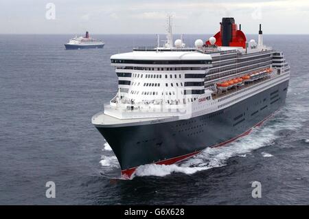 Die Queen Mary 2 (im Vordergrund) und die Queen Elizabeth 2 segeln gemeinsam in den Ärmelkanal, vorbei an Lizard Point in Cornwall. Beide Schiffe verließen New York Anfang dieser Woche, und die Amerikaner verabschiedeten sich von der QE2, deren Southampton-New York-Fahrten nun vom QM2, dem größten und teuersten Linienschiff der Welt, übernommen werden. 01/05/04: Das Ende einer Ära der Kreuzfahrt wurde heute in einer Zeremonie in Southampton mit der QE2 und Cunards neuem superliner, der 150,000 Tonnen schweren Queen Mary 2 (QM2), gefeiert. Bei der Zeremonie, an der der stellvertretende Premierminister John Prescott, Cunard's, teilnahm Stockfoto