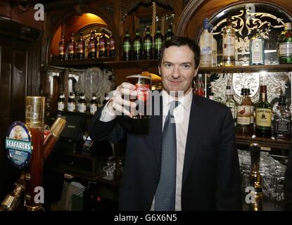 Der Schatzkanzler George Osborne hält ein Pint Bier während eines Besuchs, um den Red Lion Pub nach einer großen Renovierung in Whitehall, im Zentrum von London, offiziell wieder zu eröffnen. Stockfoto