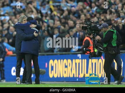 Fußball - Capital One Cup - Finale - Manchester City gegen Sunderland - Wembley Stadium. Manchester City Manager Manuel Pellegrini (links) umarmt den Sunderland Manager Gustavo Poyet nach dem letzten Pfiff Stockfoto