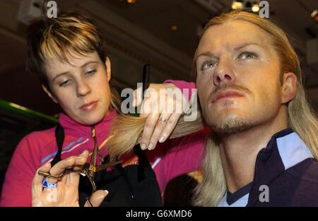 Das Wachsmodell von David Beckham lässt sich bei Madame Tussauds im Zentrum von London die Haare schneiden, während sich der hauseigene Haar- und Farbkünstler Alison Tisson darauf vorbereitet, das Erscheinungsbild des Modells nach Beckhams neuestem Haarstylwechsel zu verändern. Stockfoto