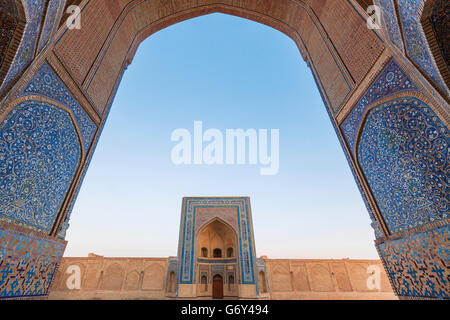 Das Tor der Moschee durch den Bogen des Poi Kalon Madrasah in Buchara, Usbekistan. Stockfoto