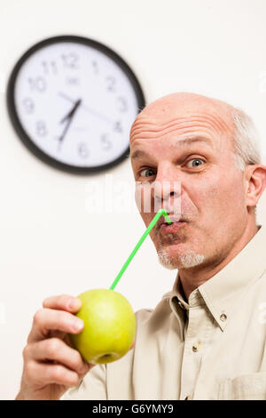 Single schöne bärtigen reifen Mann mit Glatze und vorgibt, Saft mit Stroh aus ganzen grünen Appl SIP-Hemd mit Knöpfen Stockfoto