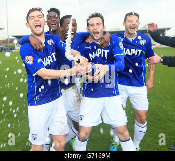 Chesterfield Jay O'Shea (links) sprüht Champagner, während sie während des Spiels der Sky Bet League 2 im Pirelli Stadium, Burton Upon Trent, die Promotion feiern. Stockfoto