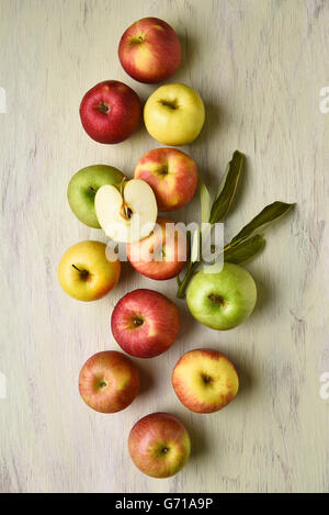 Eine Gruppe von verschiedenen Sorten von Äpfeln mit Blättern auf einem rustikalen Tisch. Hochformat aus einer hohen Blickwinkel betrachtet. Stockfoto