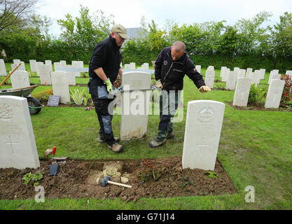 Gärtner Hausmeister First Class Myles Hunt (links) auf dem Bayeux-Kriegsfriedhof in der Normandie richten mit seinem Assistenten Jean-Claude Menoux den letzten von etwas mehr als 4,000 Grabsteinen aus, die in Bayeux ersetzt wurden, Die Commonwealth war Graves Commission (CWGC) arbeitet daran, Tausende von gefallenen und beschädigten Grabsteinen auf ihren Friedplätzen in ganz Frankreich und darüber hinaus zu ersetzen, da sie sowohl den 70. Jahrestag der Landung in der Normandie als auch den 100. Jahrestag des Ersten Weltkriegs feiert. Stockfoto