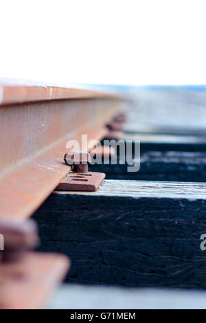Nahaufnahme von rostigen Eisenbahnstrecken überqueren eine alte Holzbrücke Stockfoto