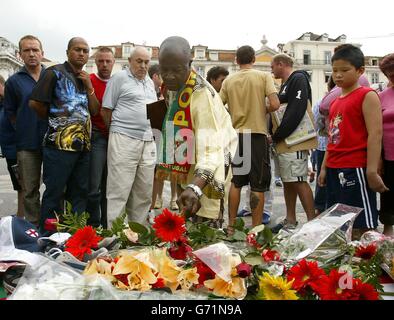 Fußballfans, Brunner und Trauernde legen Blumen an einem Schrein auf dem Rossio-Platz in Lissabon für Stephen Smith, 28, aus Wolverhampton, der während der Feierlichkeiten nach dem Euro-2004-Sieg über Kroatien erstochen wurde. Ukrainische Taschendieb Vadym Abramov, 31, wurde verhaftet und erschien heute vor Gericht. Die Tragödie ereignete sich um 3.30 Uhr in der Rua Augusta, gleich neben dem Rossio-Hauptplatz der portugiesischen Hauptstadt. Stockfoto