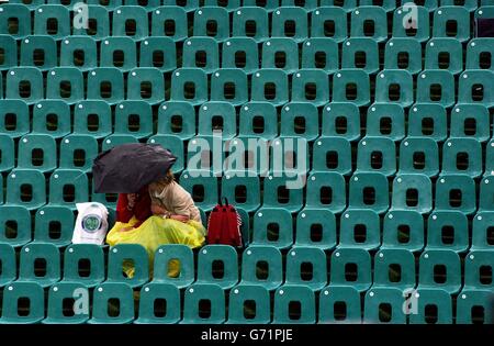 Tennisfans decken sich bei den Lawn Tennis Championships in Wimbledon, London, unter Regenschirmen ab, wo Regen und Stürme den Spielbeginn verzögerten. KEIN HANDY. Stockfoto