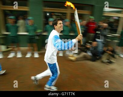 Tim Henman läuft mit der Olympic Fackel in Wimbledon durch den All England Lawn Tennis Club. Henman übergab die Flamme später an die ehemalige Meisterin Virginia Wade für die Reise nach Zentral-London. Stockfoto