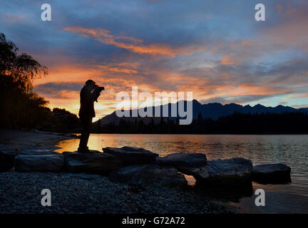 Ein Mann fotografiert den Sonnenaufgang über dem Wakatipu-See in Queenstown, neuseeländische PRESSE VERBANDSFOTO. Bilddatum: Montag, 14. April 2014. Bildnachweis sollte lauten: Anthony Devlin/PA Wire Stockfoto