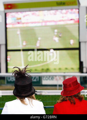 England gegen die Schweiz bei Royal Ascot. Zwei Rennfahrer sehen das Fußballspiel Euro 2004 England gegen Schweiz auf einer Großleinwand während des Ladies Day bei den Royal Ascot-Rennen. Stockfoto