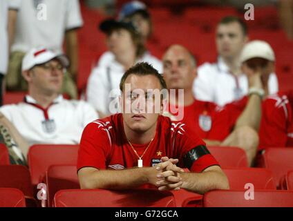 England-Fans zeigen ihre Niedergeschlagenheit nach dem plötzlichen Todesurteil im Viertelfinale der Euro 2004 gegen Portugal im Estadio da Luz in Lissabon, Portugal. England verlor gegen Portugal 6-5 auf Strafen, nachdem das Spiel in einem Unentschieden von 2-2 nach Verlängerung endete. Stockfoto