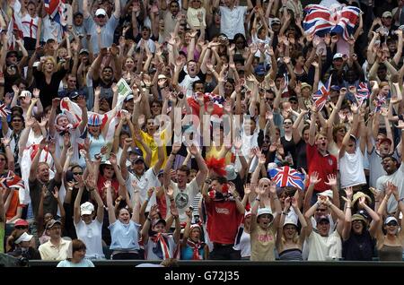 Tennisfans spielen auf dem Centre Court eine mexikanische Welle, während der britische Tim Henman bei den Lawn Tennis Championships in Wimbledon, London, Hicham Arazi aus Marokko spielt. Stockfoto