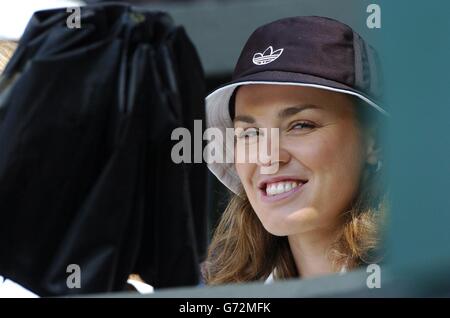 Die ehemalige Wimbledon-Meisterin Martina Hingis entrollt ihren Regenschirm, während ein Regenschauer das Spiel zwischen Landsmann Roger Federer aus der Schweiz und Sebastien Grosjean aus Frankreich im Halbfinale des Herren-Singles-Turniers bei den Lawn Tennis Championships in Wimbledon, London, unterbricht. KEIN HANDY. Stockfoto