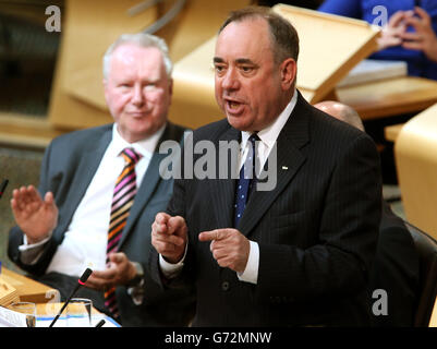 Der schottische Gesundheitsminister Alex Neil (links) hört sich den schottischen Premierminister Alex Salmond während der Fragestunde der ersten Minister im schottischen Parlament in Edinburgh an. Stockfoto