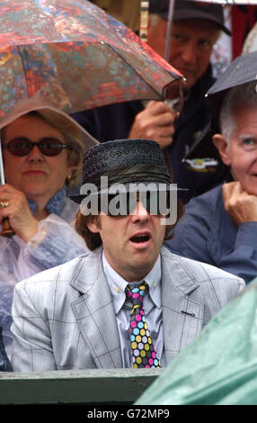 Fernsehmoderator Jonathan Ross sitzt während eines Regenschauers auf dem Center Court, der das Spiel zwischen dem Titelverteidiger Roger Federer aus der Schweiz und Sebastien Grosjean aus Frankreich im Halbfinale des Männer-Singles-Turniers bei den Lawn Tennis Championships in Wimbledon unterbrach Stockfoto