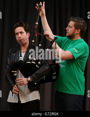 Radio 1 Frühstücksshow-Moderator Nick Grimshaw wird im National Piping Center in Glasgow von Finlay MacDonald vor dem Radio 1 Big Weekend das Spielen der Dudelsäcke beigebracht. Stockfoto