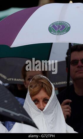 Ein Tennisfan, Court One, schützt sich vor dem Regen, der das Halbfinale des Männer-Singles-Turniers bei den Lawn Tennis Championships in Wimbledon, London, UNTERBRACH. Stockfoto