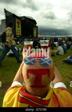 Ein Nachtschwärmer, der mit dem T-in the Park Logo auf die Hauptbühne während des zweitägigen Musikfestivals in Balado bei Stirling blickt. Stockfoto