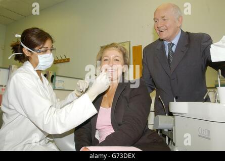 Gesundheitsminister John Reid schaut, während Gesundheitsminister Rosie Winterton in den Händen von Seema Manek (links), einem Studenten der Zahnmedizin am Dental Polyclinic, St. Thomas's Hospital, London, ist, nachdem die Regierung angekündigt hatte, bis Oktober einen Plan für die NHS-Zahnmedizin im Jahr 368 und eine Zahnarzterhöhung von 1000 zu verheißen. Gesundheitsminister John Reid versprach, weitere 1,000 Zahnärzte in den NHS zu holen, um den Service für Patienten zu verbessern. Schwere Engpässe haben zu langen Warteschlangen von Patienten geführt, die sich außerhalb neuer Zahnarztpraxen bilden, wobei weniger als die Hälfte der Erwachsenen in England jetzt bei einem NHS-Zahnarzt registriert ist. Stockfoto