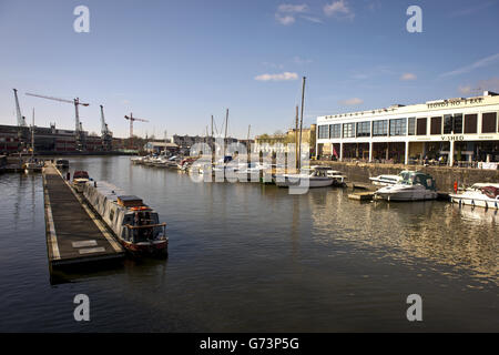 Bristol Harbour mit Blick auf die Anlegestellen und Bars am Wasser und hinaus auf das M Shed Museum im Hafen in Bristol. Es existiert seit dem 13. Jahrhundert, wurde aber zu seiner heutigen Form im frühen 19. Jahrhundert durch die Installation von Schleusentoren auf einem Gezeitenabschnitt des Flusses Avon in der Mitte der Stadt und die Bereitstellung einer Gezeitenumlauf für den Fluss entwickelt. Es wird als schwimmender Hafen bezeichnet, da der Wasserstand konstant bleibt und er nicht vom Gezeitenzustand auf dem Fluss beeinflusst wird Stockfoto