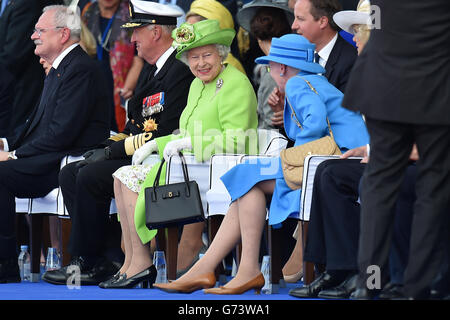 Königin Elizabeth II. Lächelt, während sie mit Königin Margrethe II. Von Dänemark spricht, während sie sich eine Aufführung ansieht, die den Prozess des D-Day bis zum Nachkriegsstück am Sword Beach während der Gedenkfeier zum 70. Jahrestag der Landung in der Normandie in Ouistreham, Frankreich, zeigt. Stockfoto