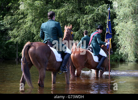 Cornet Ross Gibson carrys die Flagge mit seinen linken und rechten Männern beim zeremoniellen Eintauchen der Flagge in den Cobble Pool des River Teviot während Hawick Common-Riding in Hawick, Schottland. Stockfoto