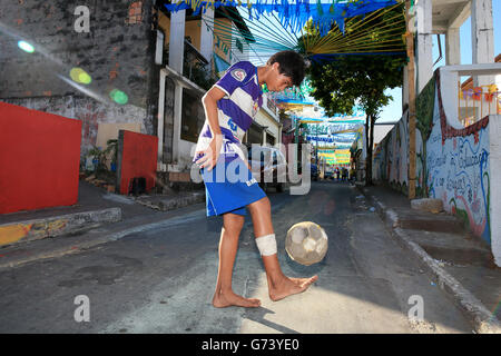 Ein junger Einheimischer spielt in den Straßen von Manaus vor dem Spiel der Gruppe D der FIFA-Weltmeisterschaft in der Arena da Amazonia, Manaus, Brasilien, einen pfiff Fußball. DRÜCKEN SIE VERBANDSFOTO. Bilddatum: Samstag, 14. Juni 2014. Siehe PA Story SOCCER England. Das Foto sollte lauten: Nick Potts/PA Wire. Keine kommerzielle Nutzung. Keine Verwendung mit inoffiziellen Logos von Drittanbietern. Keine Bildbearbeitung. Keine Videoemulation Stockfoto