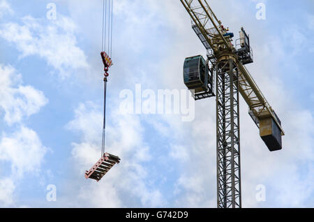 Auf der Suche an einem Kran wie bewegt er sich ein Stück Alu Gerüst (Schritte) über eine Baustelle Stockfoto