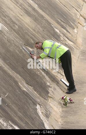 Ein Polizist untersucht die Neigung der Wand an einem Yaverland Strand in der Nähe von Sandown auf der Isle of Wight, wo ein zweijähriger Junge starb gestern getötet wurde, als ein Auto stürzte 12 Meter von einem Parkplatz auf den Strand. Stockfoto