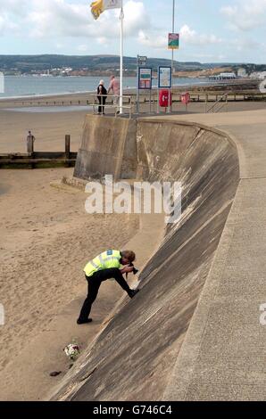 Ein Polizist untersucht die Neigung der Wand an einem Yaverland Strand in der Nähe von Sandown auf der Isle of Wight, wo ein zweijähriger Junge starb gestern getötet wurde, als ein Auto stürzte 12 Meter von einem Parkplatz auf den Strand. Stockfoto