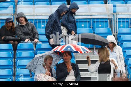 Zuschauerschutz unter Regenschirm, da das Spiel wegen Regen im Spiel Dusan Lajovic und Feliciano Lopez während der AEGON Championships im Queen's Club, London, gestoppt wird. Stockfoto