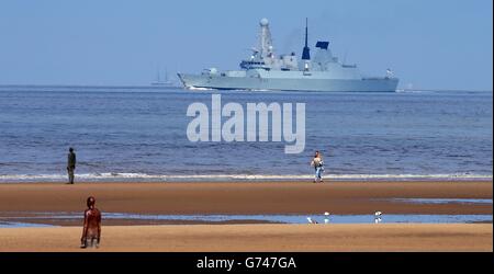 Ein allgemeiner Blick auf Antony Gormleys Skulptur Another Place am Crosby Beach während HMS Dauntless die Windfarm direkt am Strand von Crosby, Merseyside, passiert, ist das Boot Teil des Mersey River Festivals, das dieses Wochenende in Liverpool stattfindet. Stockfoto