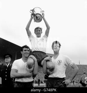 Ein fröhlicher Anblick für Tausende von Tottenham Hotspur-Fans im Empire Stadium, Wembley, als Spurs rechte Hälfte und Kapitän Danny Blanchflower den FA Cup hochhalten, der ihm gerade von der Queen nach dem Sieg von Spurs 3-1 über Burnley im Cup-Finale präsentiert wurde. Den Vorsitz von Blanchflower führen Bobby Smith (links) und Maurice Norman (Mitte). Stockfoto