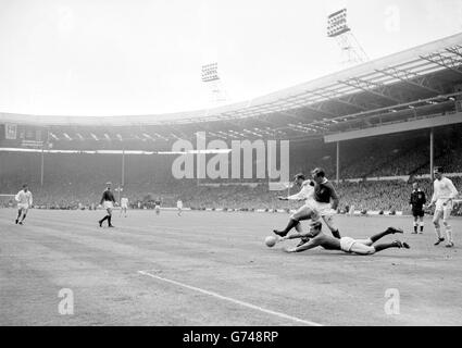 Manchester United-Torwart David Gaskell macht einen vollstreckigen Tauchgang, um den Ball während des FA-Cup-Finales in Wembley von den anstreckenden Füßen von Leicester City, innen-rechts Graham Cross (weißes Hemd) und United, der linken Hälfte Maurice Setters, zu entreißen. Stockfoto