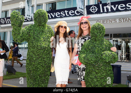 Pferderennen - Investec Ladies Day 2014 - Epsom Downs Racecourse. Rennfahrer stehen am Ladies Day auf der Rennbahn Epsom Downs am Eingang des Pavillons mit dem lebenden Topiary an Stockfoto