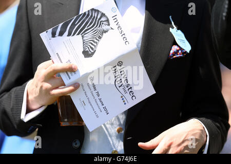 Rennfahrer lesen das offizielle Rennprogramm während des Investec Derby Day 2014 bei Epsom Downs Racecourse Stockfoto