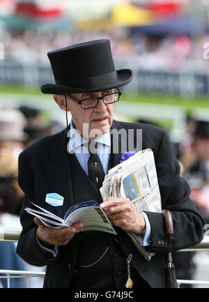 Pferderennen - Investec Derby Tag 2014 - Epsom Downs Racecourse. Ein Rennfahrer liest die Racing Post während des Investec Derby Day 2014 auf der Rennbahn Epsom Downs Stockfoto