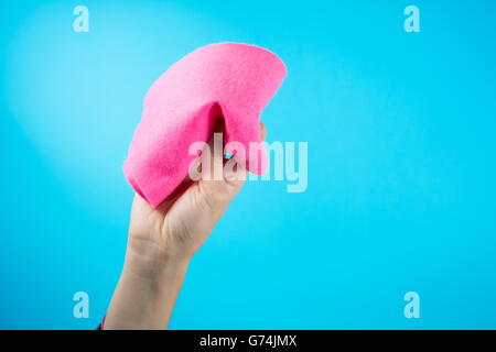 Frau Hand mit orange Reinigungstuch vor blauem Hintergrund Stockfoto