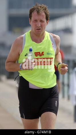 Alastair Campbell, ehemaliger Kommunikationsdirektor der Downing Street 10, spürt die Hitze während des Laufabschnitts des London Triathlon in Docklands, London, an dem er um Geld für Leukämieforschung antrat. Stockfoto