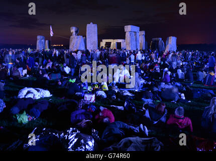 Die Menschenmassen versammeln sich kurz vor Sonnenaufgang unter den Steinen in Stonehenge in Wiltshire zur Sommersonnenwende. Stockfoto