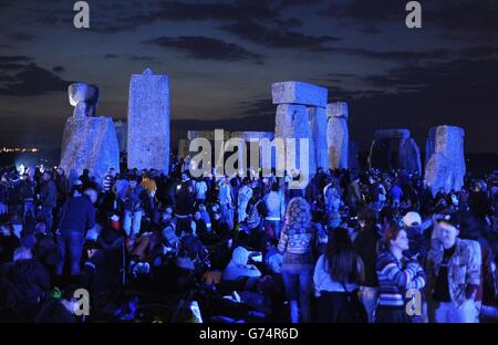 Die Menschenmassen versammeln sich vor Sonnenaufgang unter den Steinen in Stonehenge in Wiltshire zur Sommersonnenwende. Stockfoto