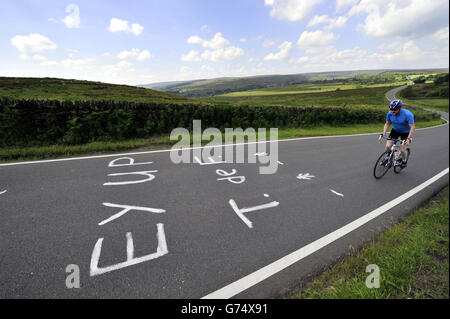 Ein Radfahrer nähert sich einem Slogan, der in Yorkshire Slang geschrieben wurde und auf den Straßen der Yorkshire Stage 2 Route der Tour de France bei Sheffield gemalt wurde. Die zweite Etappe startet in York und endet in Sheffield. PRESSEVERBAND Foto: Ausgabedatum: Mittwoch, 25. Juni 2014. Photo Credit sollte John Giles/PA lesen Stockfoto