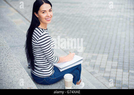 Fröhliche Frau, die sich Notizen macht Stockfoto