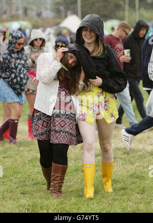 Glastonbury Festival 2014 - Vorbereitungen. Festivalbesucher bei einem Regenschauer beim Glastonbury Festival auf der Worthy Farm in Somerset. Stockfoto