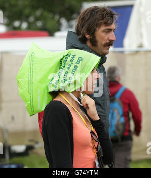 Festivalbesucher während eines Regenschauers auf dem Glastonbury Festival, würdig Farm in Somerset. Stockfoto